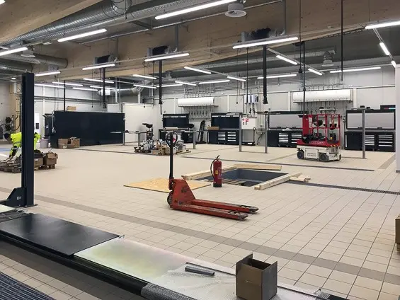Kuva korjaamohallista keskeneräisenä. Vaalea kaakelilattia, jossa tummemmet yksityiskohdat.