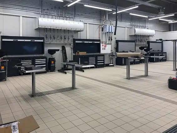 Todellinen kuva samasta kulmasta kuin 3D-malli. Asentajan työpisteillä lattiaan upotetut nosturit, sekä työkalukaapit ja öljykelat.