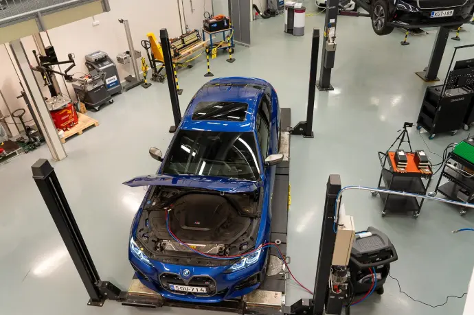 Kuva ylöviistosta kahden nosturin korjaamohalista, jossa BMW nelipilarinostimella ilmstaointihuollossa.